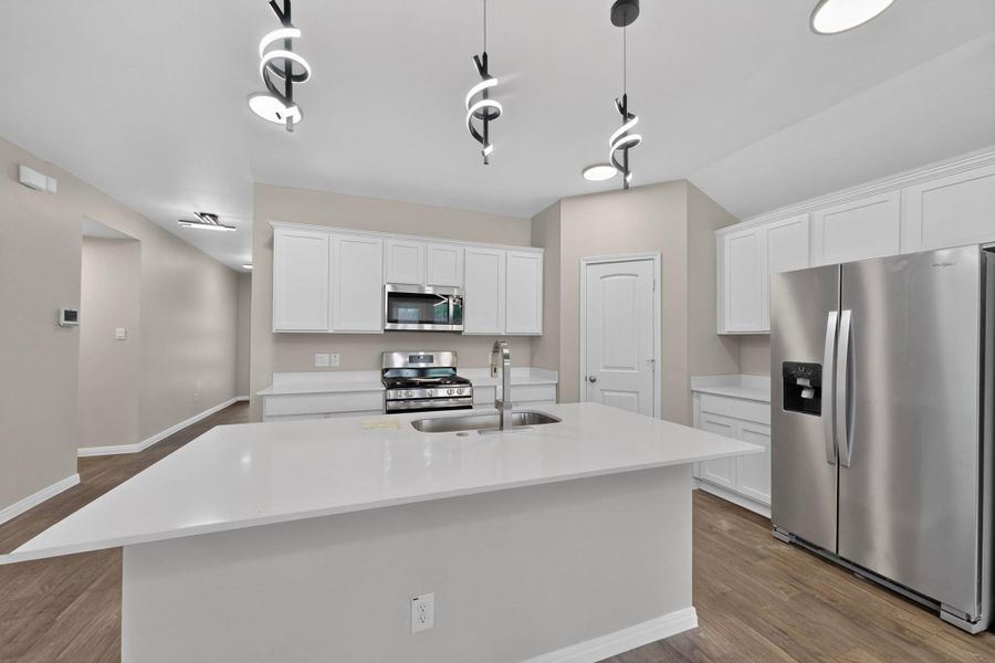 Crisp white cabinetry paired with durable wood-look flooring defines this modern kitchen workspace.