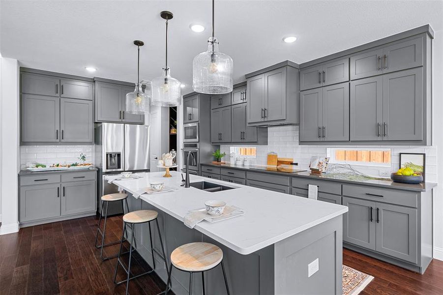 Kitchen with gray cabinetry, decorative backsplash, appliances with stainless steel finishes, dark wood-style floors, and recessed lighting