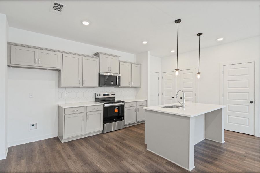 Kitchen featuring light grey cabinetry, stainless steel appliances, white hexagon tile backsplash, and wood-finish flooring
