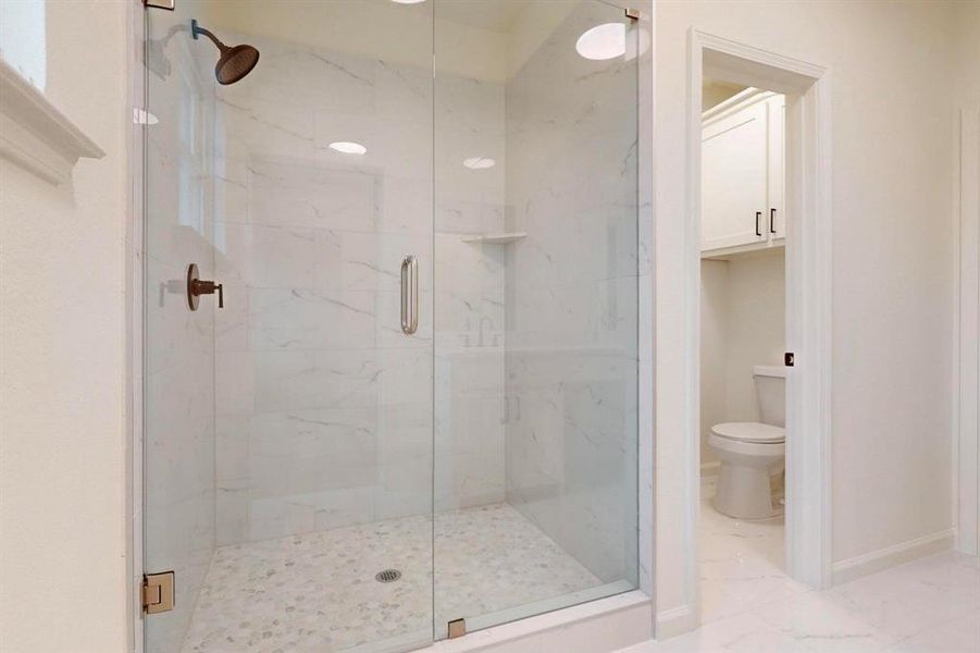 Bathroom featuring a marble finish shower, marble finish floor, toilet, and baseboards