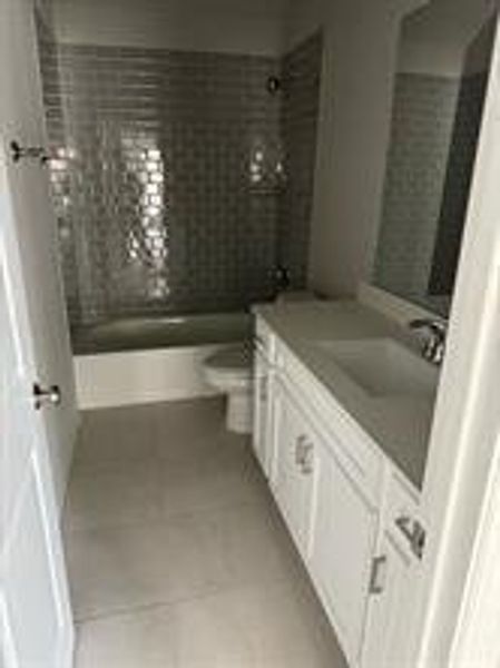 Full bathroom featuring tiled shower / bath, tile patterned flooring, vanity, and toilet