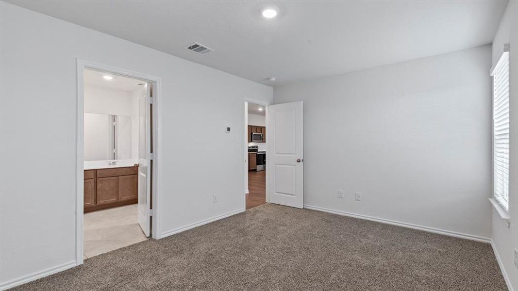 Unfurnished bedroom with light colored carpet, ensuite bath, and recessed lighting
