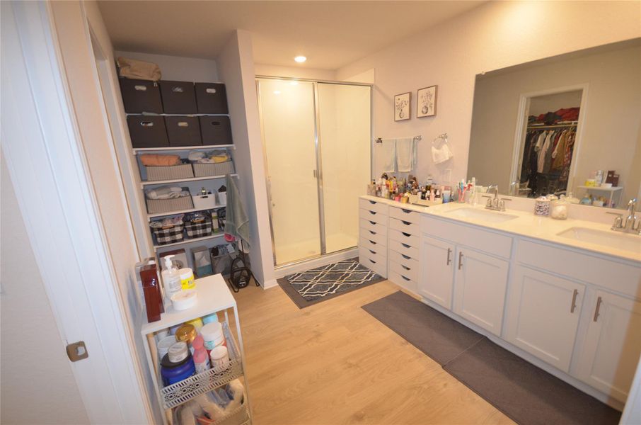 Full bath with a shower stall, wood finished floors, double vanity, a spacious closet, and recessed lighting Full bath with a shower stall, wood finished floors, double vanity, a spacious closet, and recessed lighting