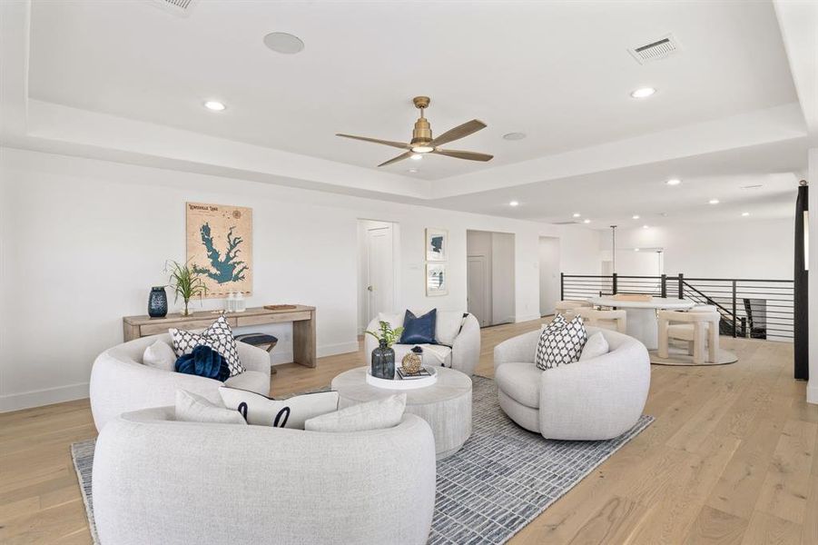 Living room featuring a tray ceiling, light wood-type flooring, recessed lighting, and ceiling fan Living room featuring a tray ceiling, light wood-type flooring, recessed lighting, and ceiling fan