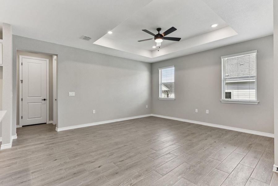 Unfurnished room with light wood-type flooring, a tray ceiling, a ceiling fan, and recessed lighting