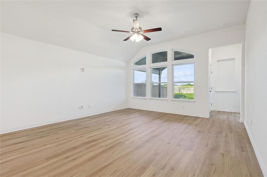 Empty room with lofted ceiling, ceiling fan, and light hardwood / wood-style flooring