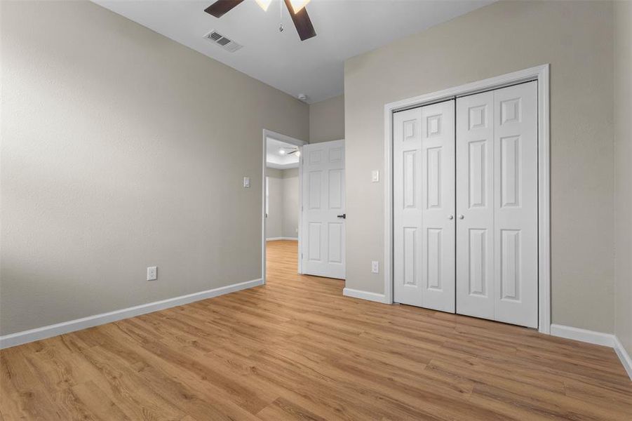 Unfurnished bedroom with light wood-style flooring, a closet, and a ceiling fan