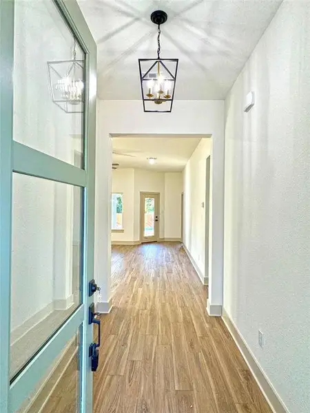 Hall with light wood-style flooring and a chandelier