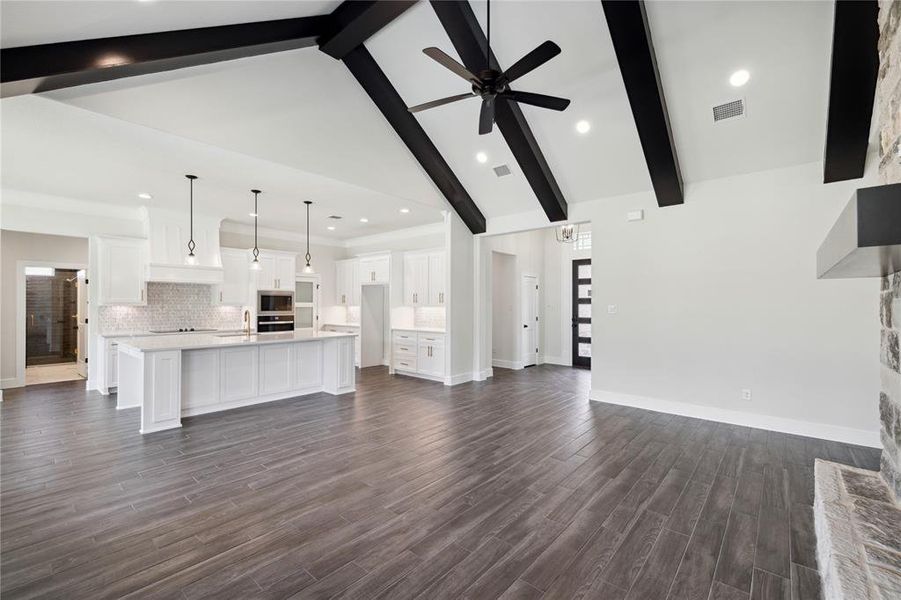 Unfurnished living room with ceiling fan, dark hardwood / wood-style floors, beamed ceiling, sink, and high vaulted ceiling