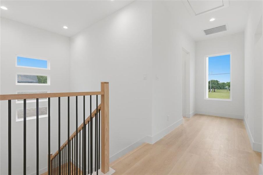 Upper-level hallway featuring light wood-finish flooring, recessed lighting, and white walls Upper-level hallway featuring light wood-finish flooring, recessed lighting, and white walls