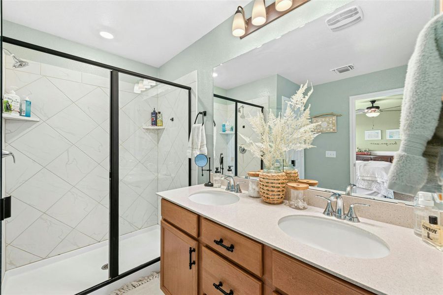 The primary bedroom features an ensuite bathroom complete with a sophisticated double vanity and a beautifully tiled shower stall with sleek glass doors, creating a refined and inviting private retreat.