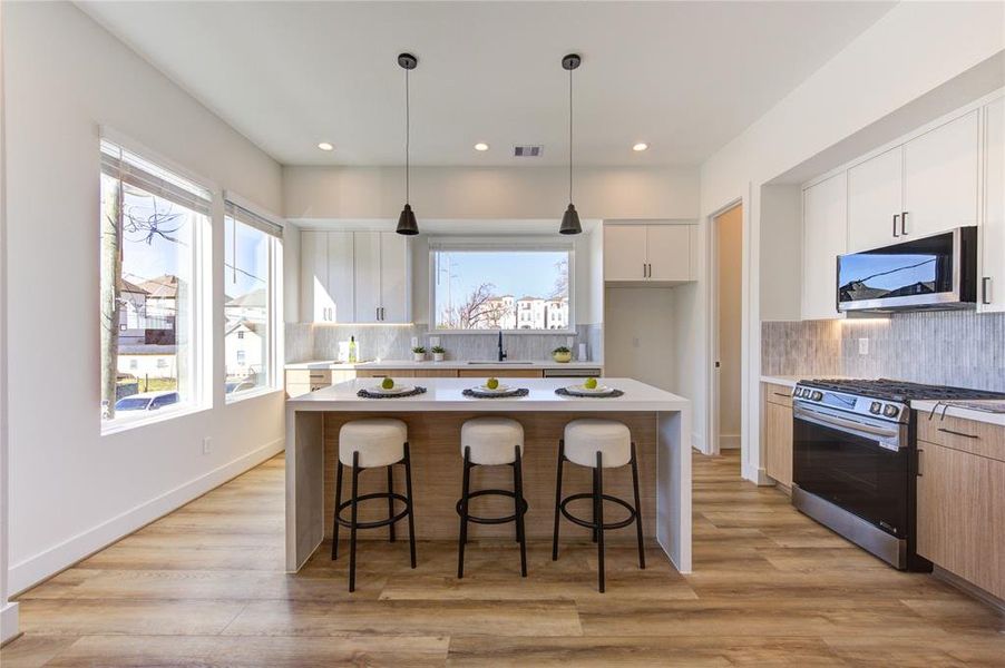 Natural light floods this stunning kitchen with views of East River overlooking the sink! This kitchen features European style white oak and white slim shaker soft-close cabinetry, beautiful custom tile backsplash, white quartz with a 2 inch thick waterfall island, and large walk-in corner pantry.