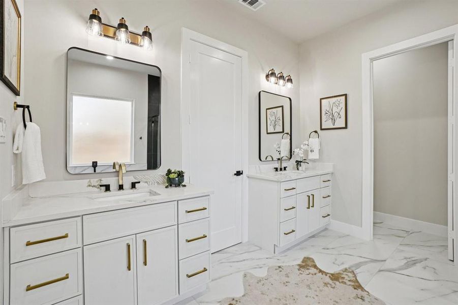 Full bath featuring two vanities and light marble finish floors