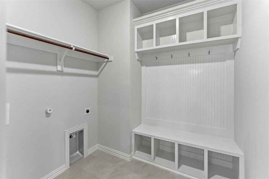 Built-in white storage bench with open cubbies, beadboard backing, and overhead shelving featuring integrated coat hooks