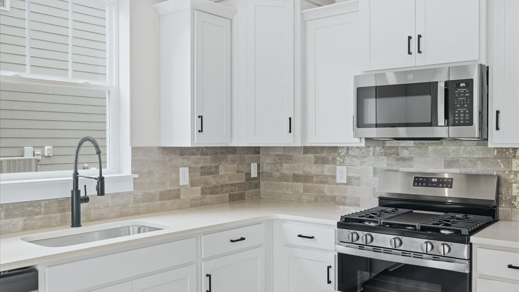 Superior kitchen with quartz countertops, white cabinets, and stainless steel appliances at Creeks at Midway