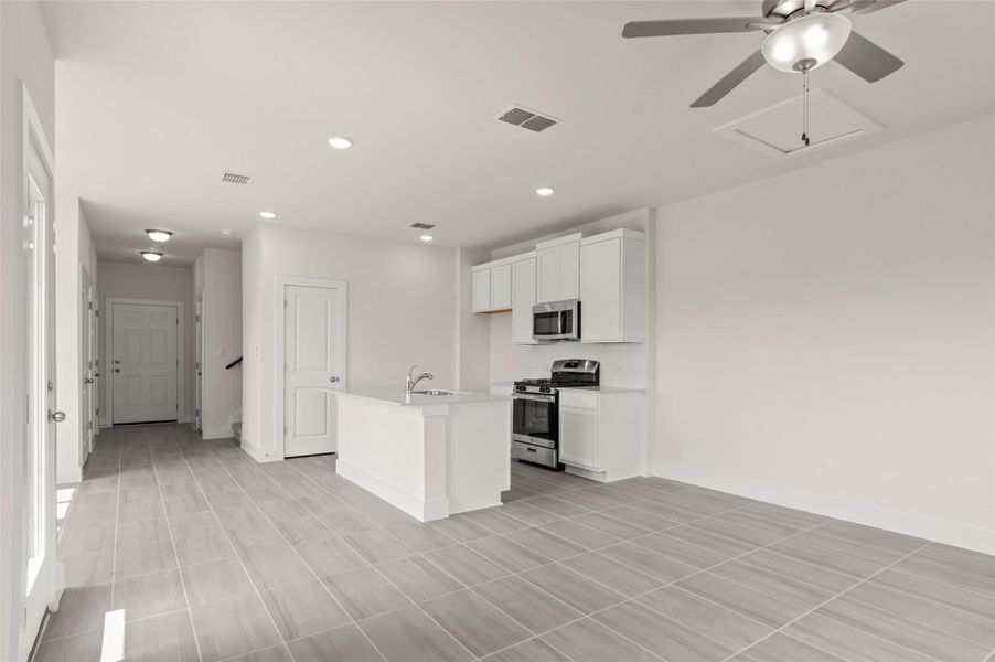 Kitchen with visible vents, a ceiling fan, white cabinets, a sink, and appliances with stainless steel finishes