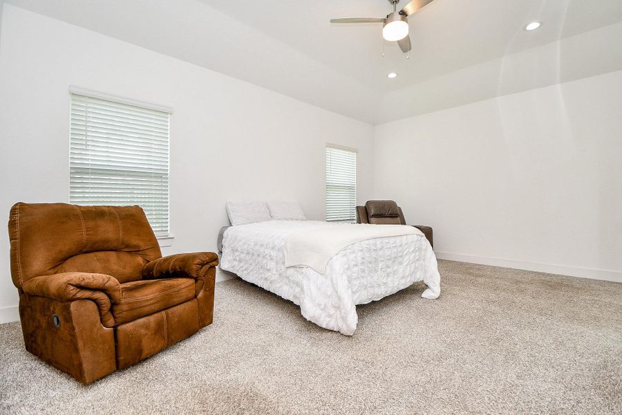 This spacious primary bedroom, located on the first floor, features neutral carpeting and walls, providing a cozy atmosphere. It includes a ceiling fan, and ample natural light from two windows, perfect for relaxation. This spacious primary bedroom, located on the first floor, features neutral carpeting and walls, providing a cozy atmosphere. It includes a ceiling fan, and ample natural light from two windows, perfect for relaxation.