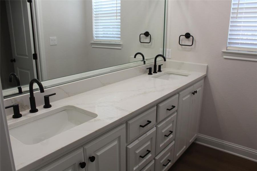 Full bathroom with double vanity, plenty of natural light, baseboards, and wood finished floors Full bathroom with double vanity, plenty of natural light, baseboards, and wood finished floors
