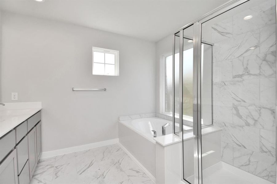 Featuring a massive walk-in shower with tile surround. Slate colored cabinets with light granite countertops complement the space. An ideal retreat for unwinding after a long day. Sample photo of completed home with similar floor plan. As-built interior colors and selections may vary.