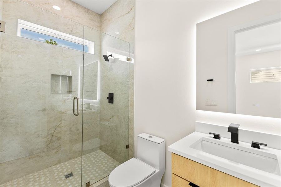 Bathroom featuring a glass-enclosed shower with full-height tile surround, a built-in shower niche, and a transom window