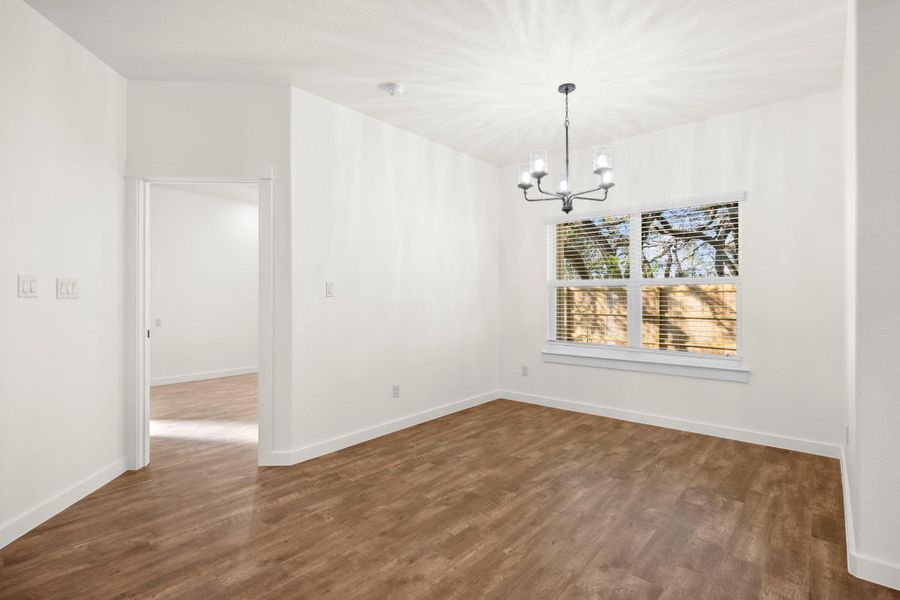 A versatile interior space featuring durable laminate flooring and an elegant chandelier, awaiting your personal touch.