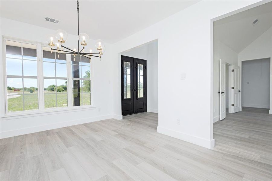 Unfurnished dining area with a chandelier, plenty of natural light, light wood-type flooring, and lofted ceiling