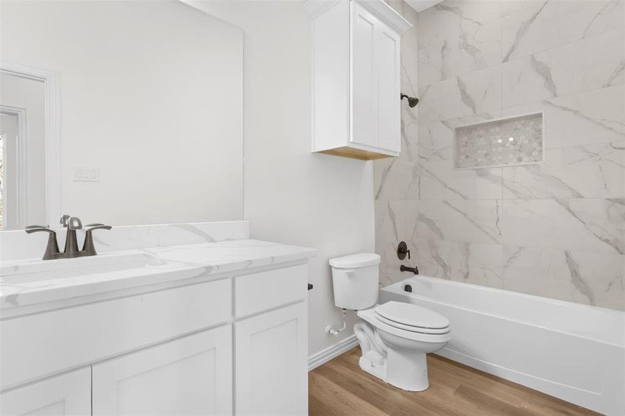 Full bathroom featuring vanity, toilet, wood-type flooring, and tiled shower / bath