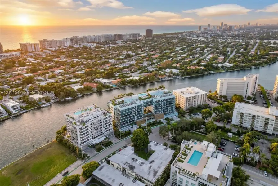 Aerial perspective featuring waterfront placement, proximity to the coastline, multi-story structural architecture, and rooftop recreational spaces