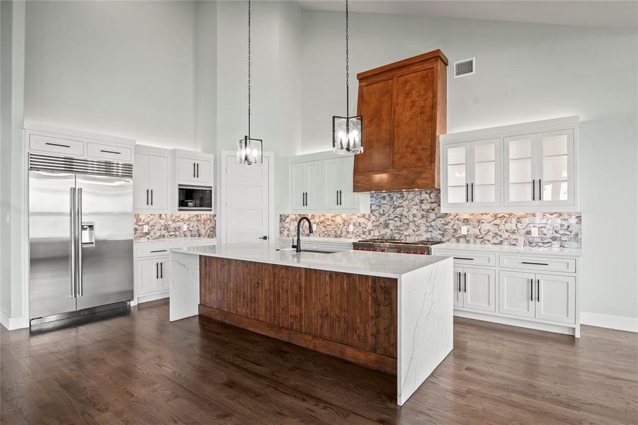Dual pantries provide exceptional kitchen storage. Warm wood floors complement the home’s modern lakefront design.