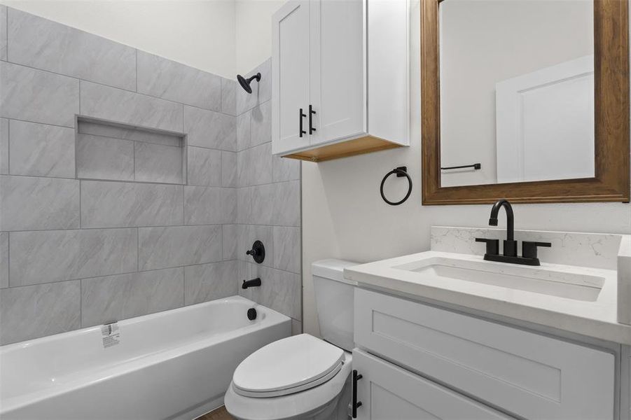The bathroom features a white bathtub with light-colored tile surround, a built-in shower niche, and matte black fixtures