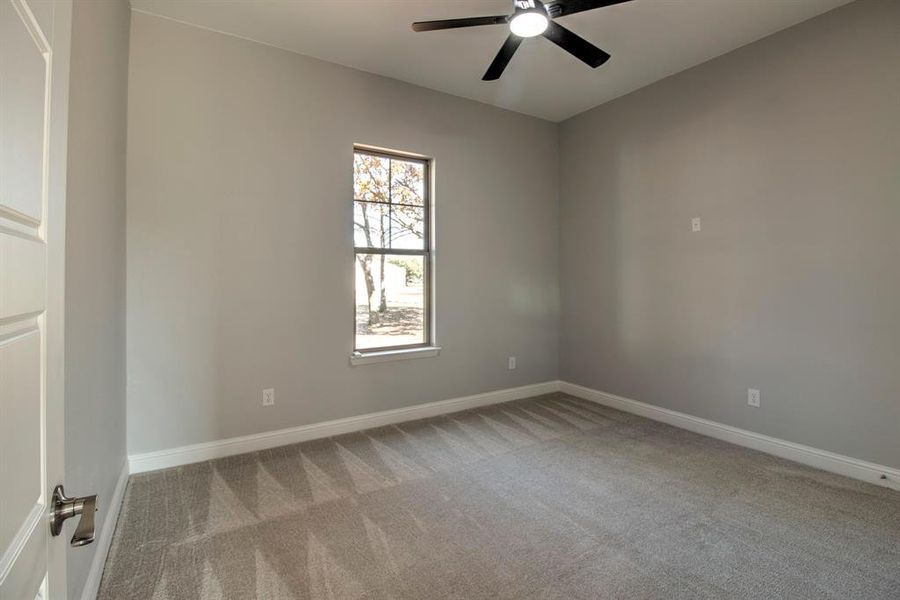 Empty room with ceiling fan and light colored carpet