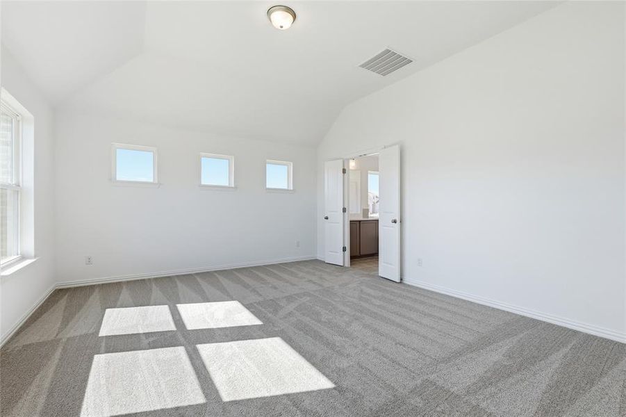 Spacious room featuring vaulted ceilings, a large window, three smaller accent windows, and plush patterned carpeting