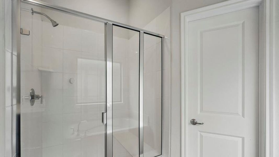 Full glass shower enclosure featuring a chrome showerhead, polished chrome controls, and white subway tile surround
