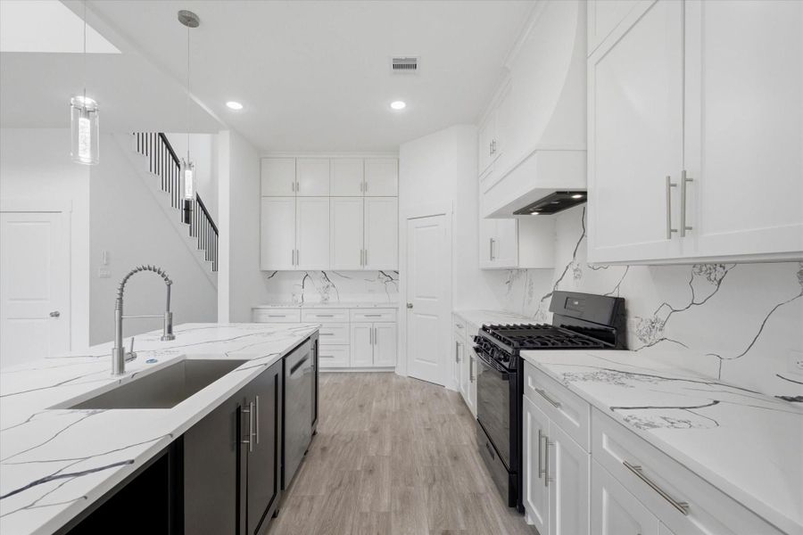 This kitchen features a modern color palette, a 5-burner gas stove, and soft-close cabinets and drawers, plus designated cabinetry for the microwave, trash bin, and more. This kitchen features a modern color palette, a 5-burner gas stove, and soft-close cabinets and drawers, plus designated cabinetry for the microwave, trash bin, and more.