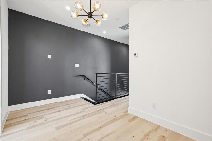 Spare room featuring a notable chandelier and light hardwood / wood-style flooring