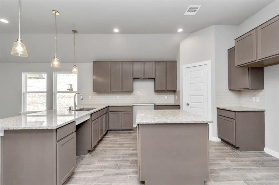 Discover another perspective of this stunning kitchen, generously appointed with an abundance of counter space.  Sample photo of completed plan. As-built color and selections may vary.