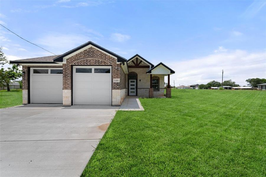 View of front facade with concrete driveway, a garage, a front lawn, stone siding, and brick siding View of front facade with concrete driveway, a garage, a front lawn, stone siding, and brick siding