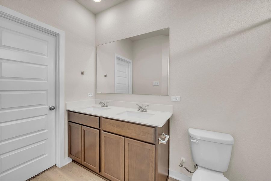 Full bathroom featuring double vanity and light wood-style flooring