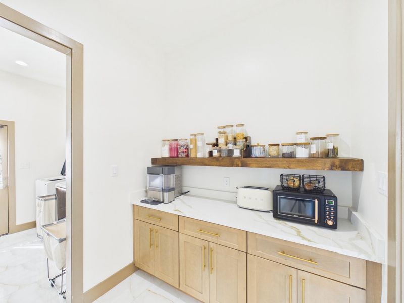 Additional kitchen storage with built in cabinetry, counter space, and open shelving.