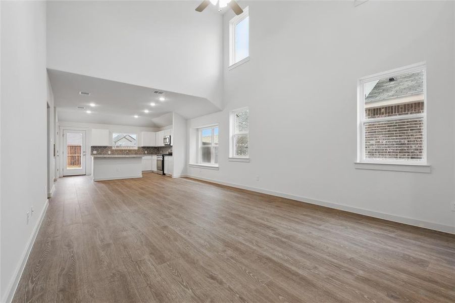 Unfurnished living room with a wealth of natural light, light wood-type flooring, and baseboards Unfurnished living room with a wealth of natural light, light wood-type flooring, and baseboards