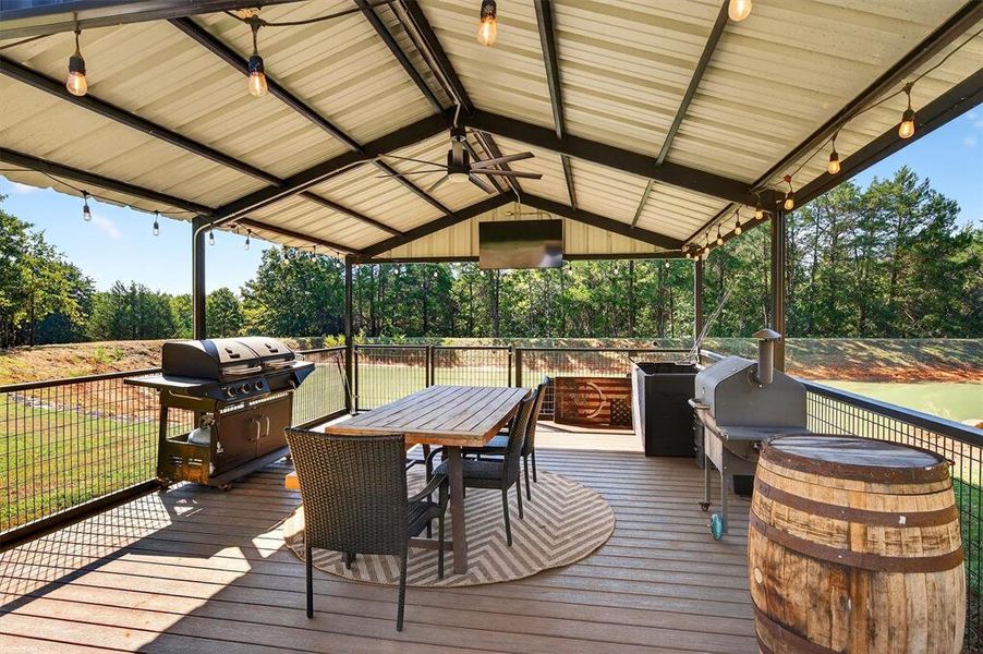 Wooden terrace with outdoor dining space, area for grilling, and view of wooded area Wooden terrace with outdoor dining space, area for grilling, and view of wooded area