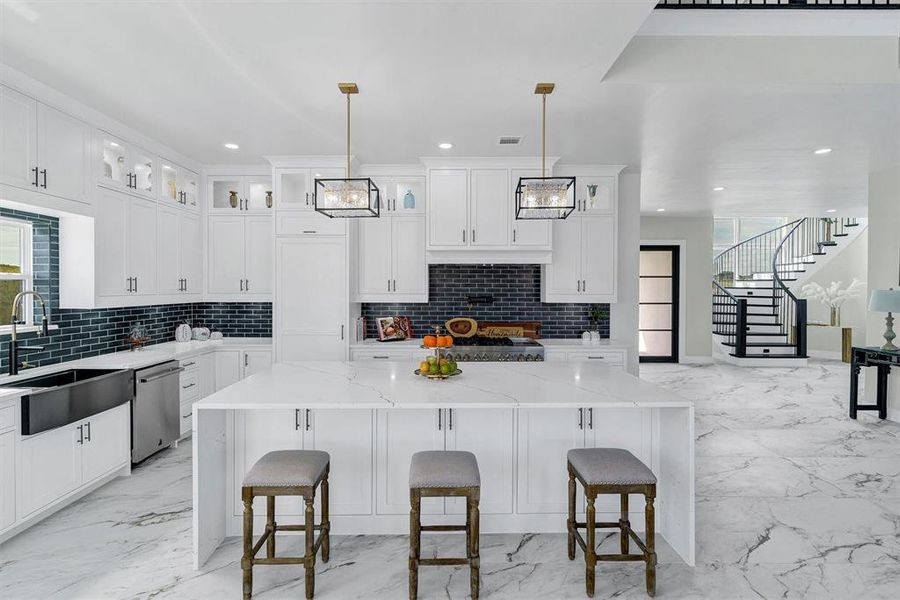 Kitchen with light stone counters, tasteful backsplash, a kitchen island, and hanging light fixtures