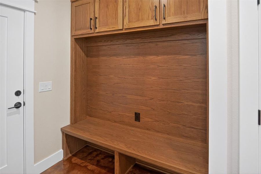 Built-in hall tree featuring wood-finish cabinetry with matte black hardware, integrated bench seating, and an open storage cubby Built-in hall tree featuring wood-finish cabinetry with matte black hardware, integrated bench seating, and an open storage cubby