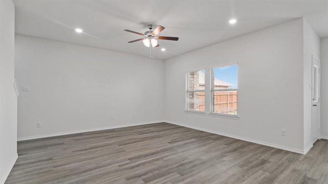 Spacious room featuring wood-finish flooring, recessed lighting, and a ceiling fan Spacious room featuring wood-finish flooring, recessed lighting, and a ceiling fan