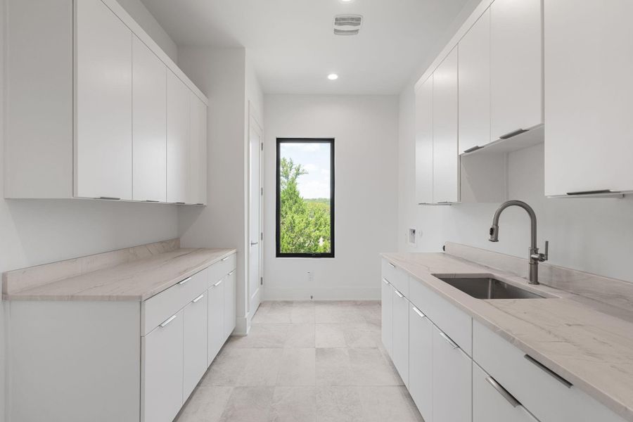Ample storage and a deep utility sink make this well-appointed laundry room highly functional.