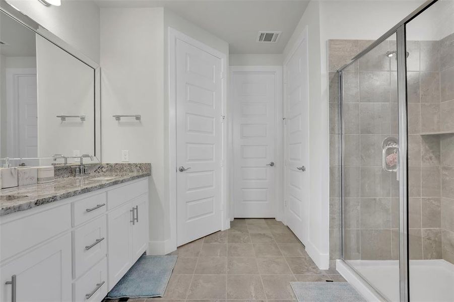 Bathroom featuring vanity, tile patterned floors, and a shower with door