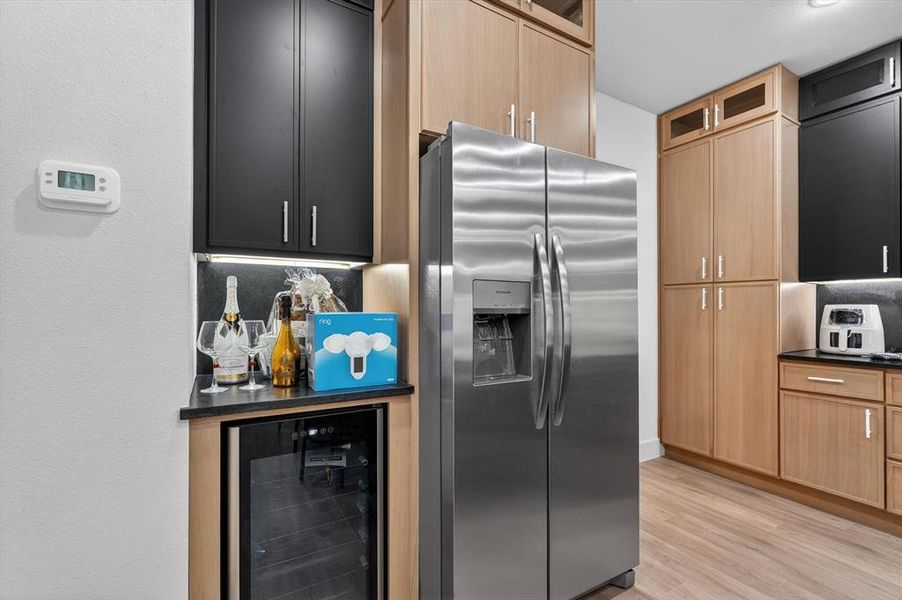 Contemporary kitchen with two-tone cabinetry, featuring light wood-finish and matte black upper cabinets