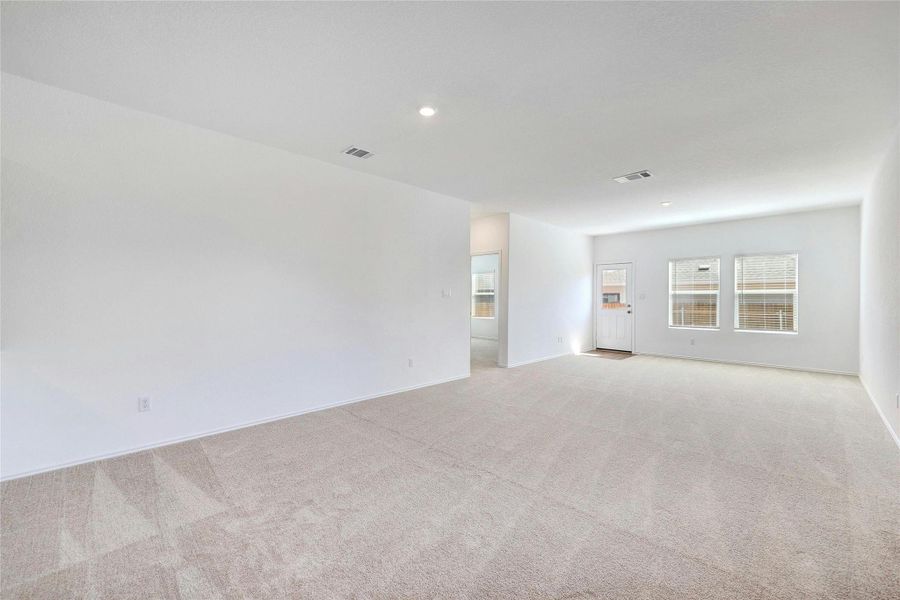 Empty room with light carpet and recessed lighting