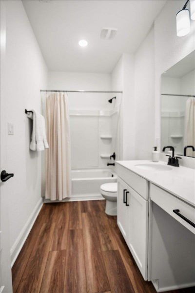 A clean, modern bathroom featuring rich wood-look flooring and contrasting dark fixtures.