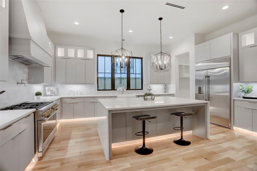 The waterfall-island kitchen provides ample room for prepping, cooking, and entertaining. You'll appreciate the 48" range and hood, built-in refrigerator, breakfast bar, and walk-in pantry. The kitchen also features toe kick lighting as an added wow element.